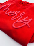 Red sweatshirt with pink 'Merry' text on a white background